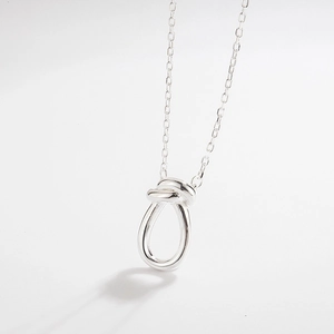 Macro shot of minimalist silver knot pendant with polished mirror finish on a link chain
