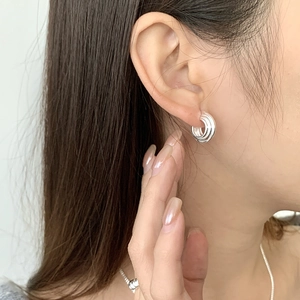 Dettaglio degli orecchini a cerchio triplo in argento sterling S925 indossati da un modello
