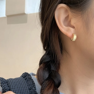 Macro shot of gold-plated S925 silver earrings with pleated texture and C-shape design