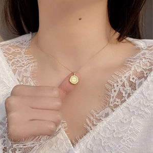 Collier en argent 925 doré avec pendentif rond gravé porté par un mannequin