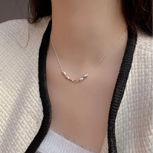 Gros plan de cinq pendentifs grains en argent sur un collier ras du cou en argent 925