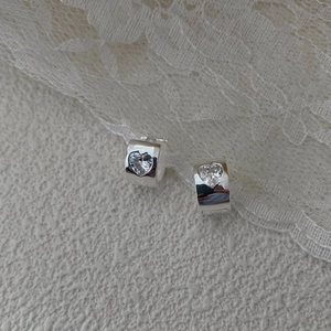Detail shot of S925 sterling silver heart zircon earrings on a lace background