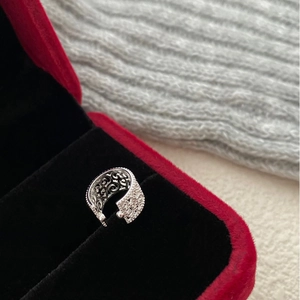 Macro view of vintage silver hollow carved cuff with intricate scrollwork on red velvet