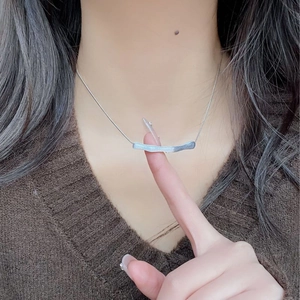 Macro shot of 925 sterling silver brushed irregular bar pendant on minimalist necklace