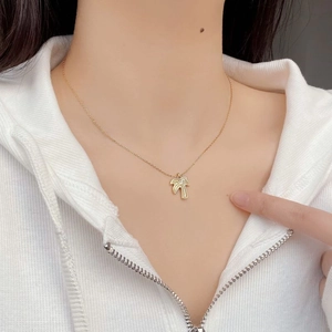 Detailed view of a minimalist gold coconut tree pendant necklace on a model neck