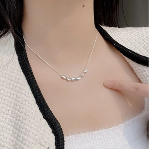 Détail du collier de perles en argent S925 porté sur le cou avec veste en tweed