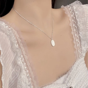 Detailed view of an oval 925 silver necklace with white inlay on a lace collar