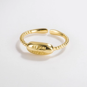 Detail of gold twisted band ring featuring an oval plate with 'as you wish' engraving