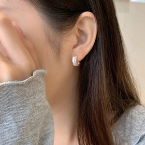 Close-up of S925 sterling silver hoop earrings with textured gear design on model ear