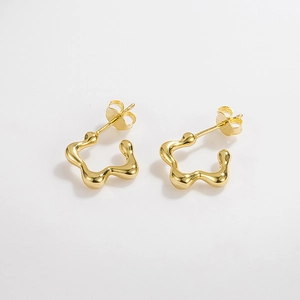 Détail de boucles d'oreilles dorées irrégulières à motifs ondulés et fermoirs papillon