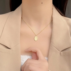 Minimalist 925 silver oval pendant necklace in gold finish on a model with a blazer