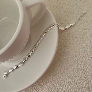 Close-up of polished S925 sterling silver beaded bracelet hanging on a white ceramic cup