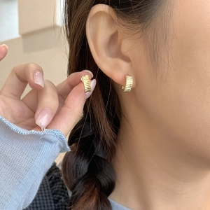 Minimalist gold S925 sterling silver pleated gear earrings shown on an ear and hand