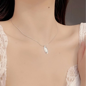 Close-up of S925 silver necklace with oval white agate pendant on model neck