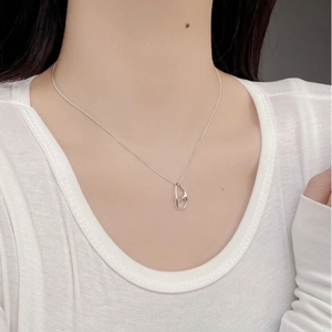 Close-up of minimalist silver irregular pendant necklace on model with white top
