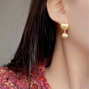 Detail of matte brushed gold double ball earrings on model for an elegant look