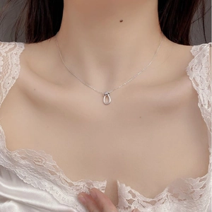 Detail of S925 sterling silver U-knot necklace worn on neck with white lace background
