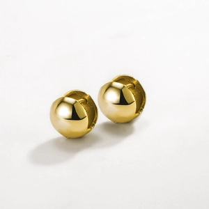 Vue macro de boucles d'oreilles créoles sphériques en or poli et argent fin 925