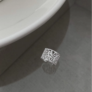 Close-up of silver hollow carved floral pattern ring with adjustable open band