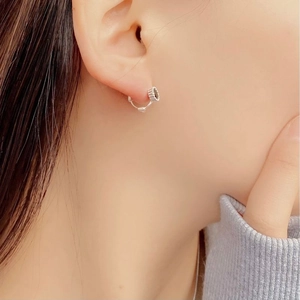 Close-up of S925 sterling silver hoop earrings with micro-beaded texture on model ear