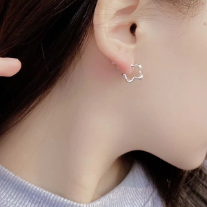 Gros plan de boucles d'oreilles vagues argentées sur mannequin au design métal liquide