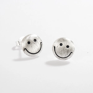 Macro detail of S925 sterling silver stud earrings featuring brushed metal and smiley faces
