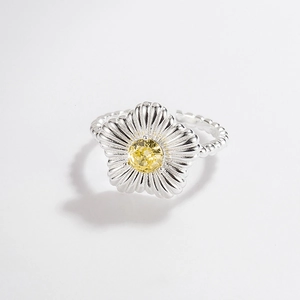 Detail of silver flower ring with yellow gemstone and textured petals on beaded band