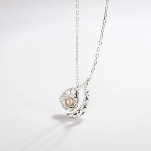 Detailed close-up of textured moon pendant and pearl drop on 925 silver cable chain