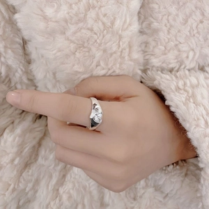 Detailed view of silver S925 heart zircon ring with wide textured band on hand