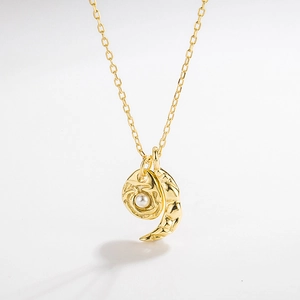Detailed macro shot of textured gold round pendant with white pearl and crescent moon charm