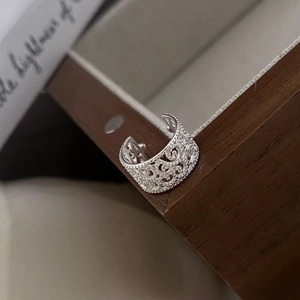 Close-up of S925 silver ear cuff with hollowed floral patterns on a vintage wooden box