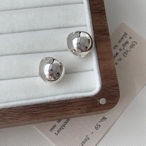Détail macro de boucles d'oreilles boules en argent S925 sur un plateau à bijoux blanc
