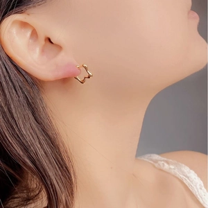 Gros plan sur des puces d'oreilles étoile en or 18K avec une finition miroir polie