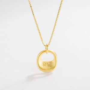 Close-up of matte gold pendant with bliss engraving on a fine box chain necklace