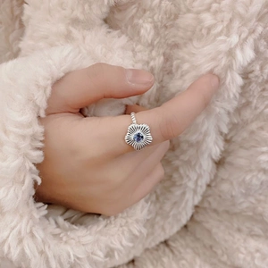 Detailed view of silver flower ring with central blue gemstone worn on hand