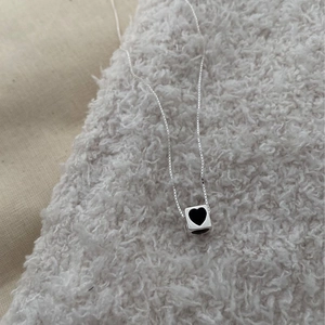 Detail of silver S925 necklace featuring a black heart cube pendant on soft fleece