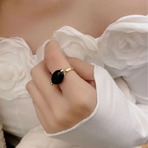 Close-up of minimalist gold ring featuring a large oval black onyx stone on a hand