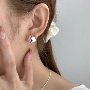 Gros plan d'une boucle d'oreille minimaliste en argent S925 poli en forme de sphère