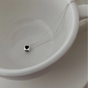 Minimalist S925 silver cube pendant necklace with black heart detail in a ceramic bowl