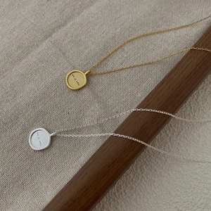 Close-up of gold and silver letter engraved round coin pendants on cross chains