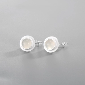 Détail macro de boucles d'oreilles vintage en argent mat avec agate blanche translucide