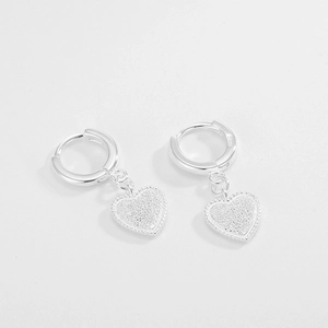 Macro detail of S925 sterling silver heart earrings with frosted finish and bead trim