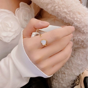 Close-up of a heart-shaped white mother-of-pearl gold ring on a woman's finger