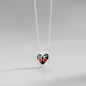 Close-up of heart pendant with cherry enamel and silver beaded chain detail
