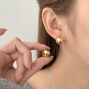 Détail de boucles d'oreilles boules dorées polies avec un fini miroir métallique