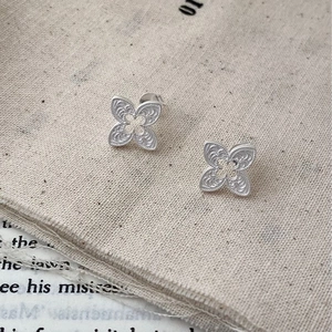 Macro shot of silver S925 clover earrings with intricate filigree texture on fabric