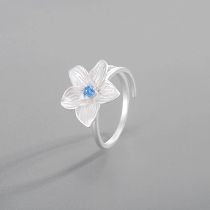 Macro shot of silver hibiscus flower ring with blue crystal center and textured petals