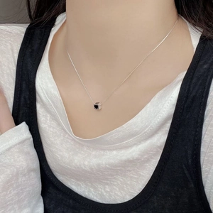 Close-up of S925 sterling silver cube pendant with black heart on model neck