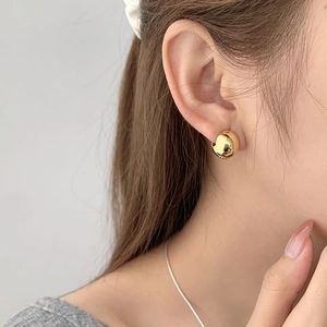 Gros plan de boucles d'oreilles en argent doré en forme de haricot avec fini miroir chic