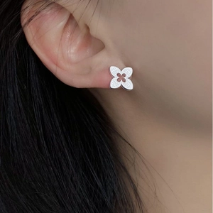 Macro close-up of S925 sterling silver clover earrings with radial texture on the ear